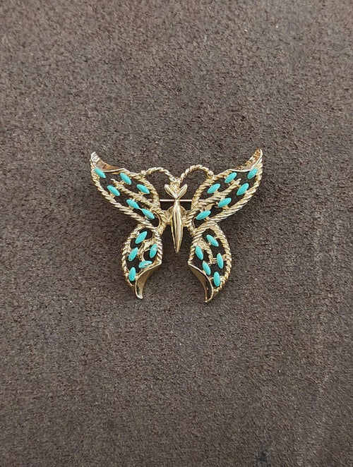 Gold-tone butterfly brooch with faux turquoise enamel wing accents, viewed from front