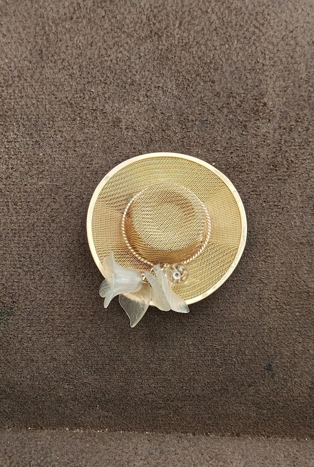 Gold-tone mesh sun hat brooch pin lying flat with dangling white angel charm
