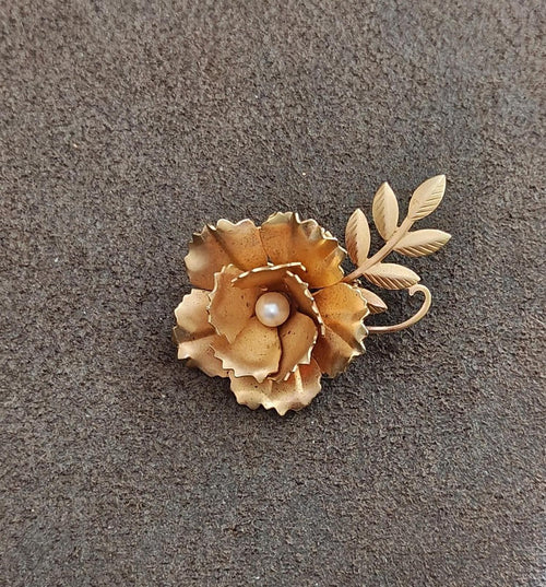 Gold-tone floral brooch with faux pearl at center and leaf-like accents