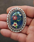 Silver-tone oval brooch pendant with blue art glass and multicolor flower quilling