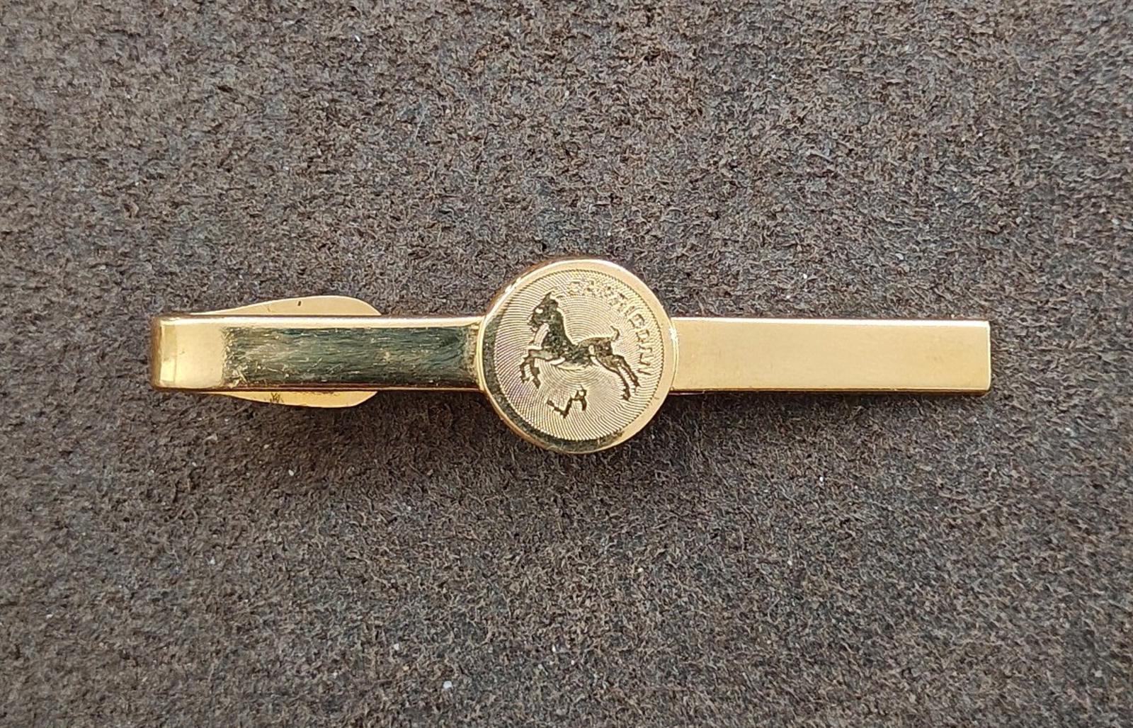 Gold-tone tie bar with centered Capricorn medallion and straight bar design
