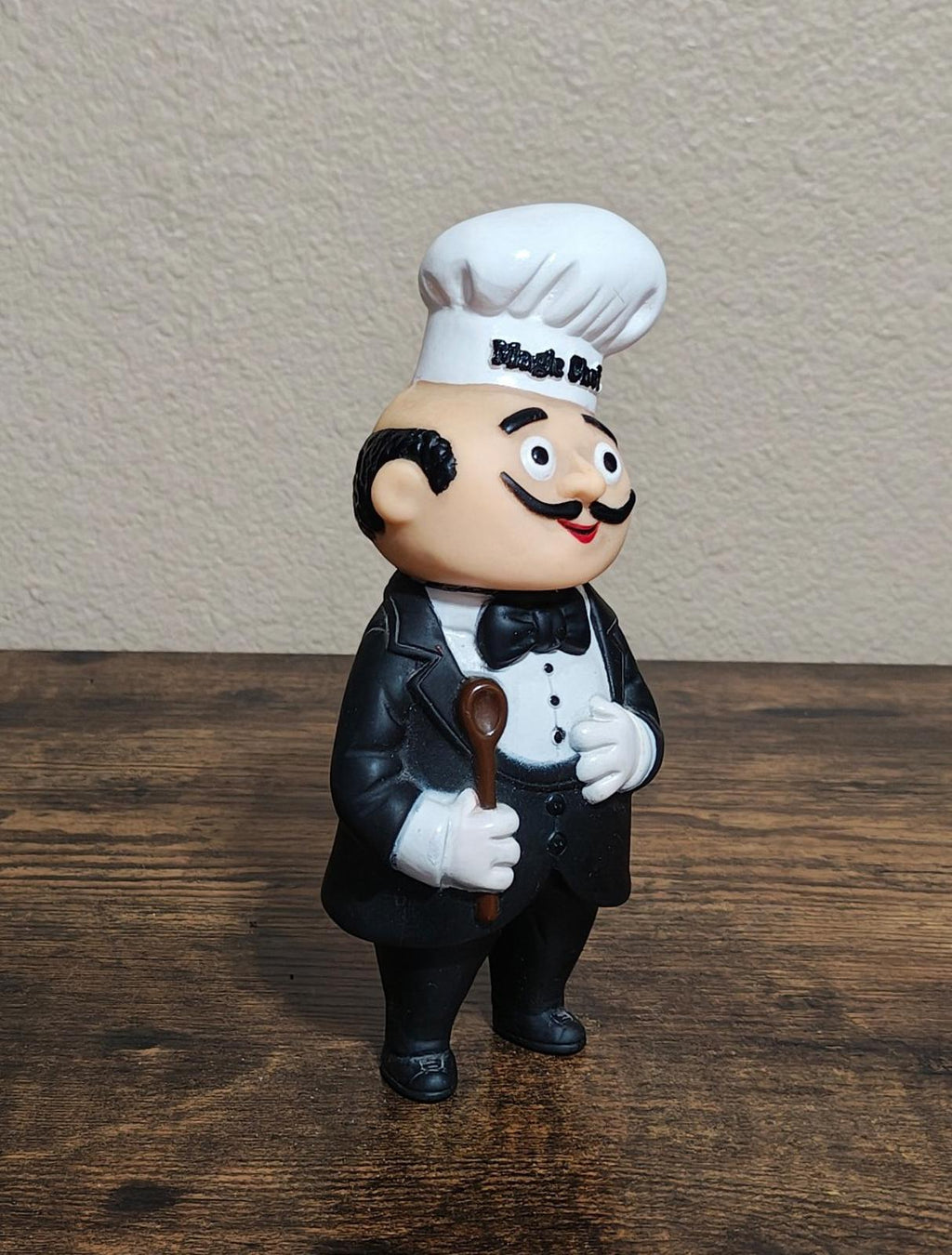 Black chef coin bank figurine holding utensil, full-body view