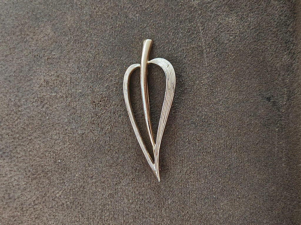 Gold open leaf brooch with tall center stem and leaf-shaped textured outline.