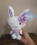 Plush bunny with purple-and-white striped outfit, curled top hat, and smiling face