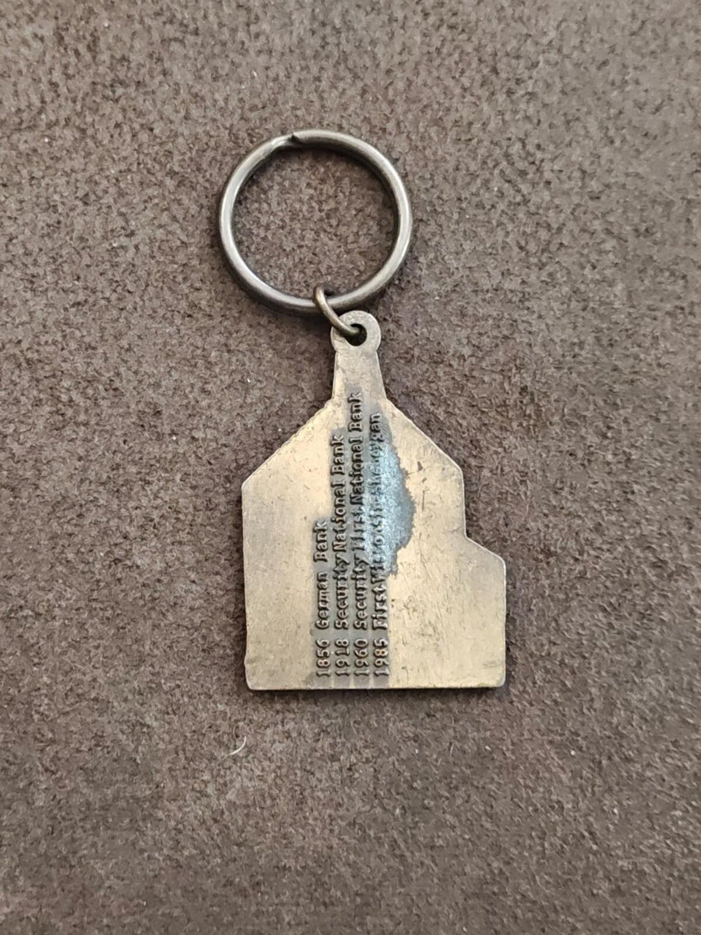 Metal keychain tag with engraved address and year lines plus circular ring