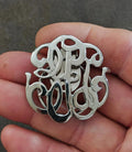 Silver-tone monogram scarf clip with ornate cutout lettering and polished details