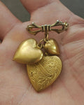 Gold-tone three-heart bow dangle brooch with heart charms and clasp pin