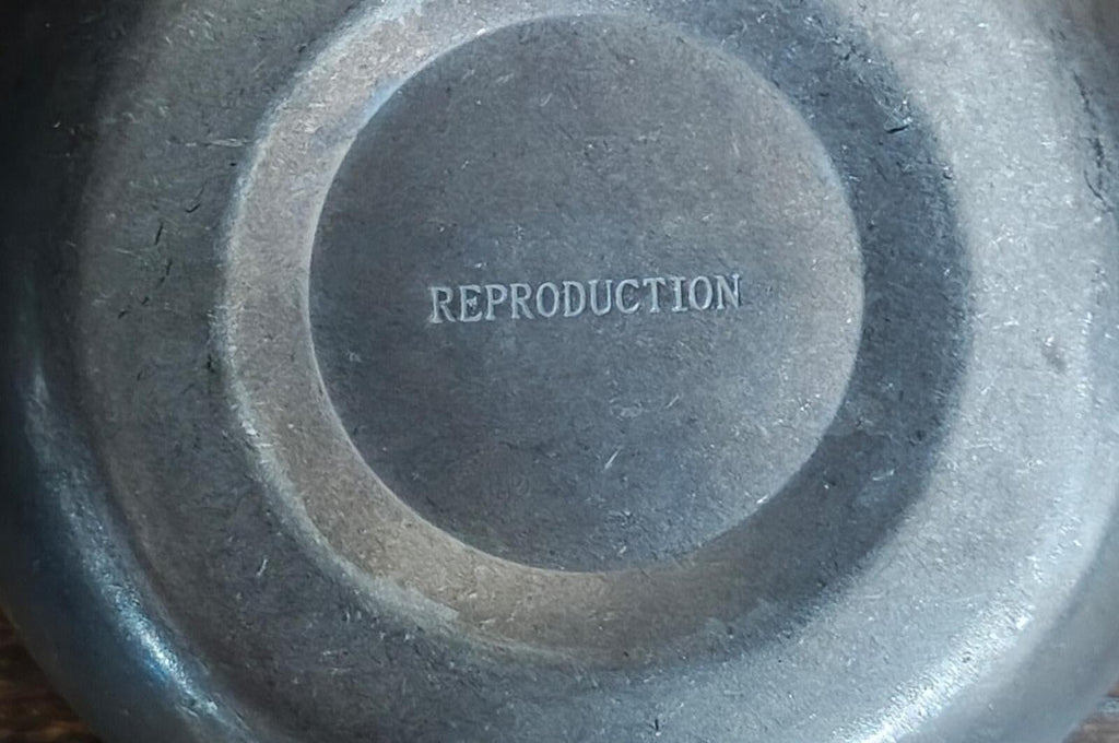 Close-up of stainless steel mug base with embossed text REPRODUCTION
