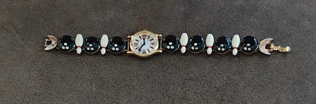 Novelty ladies watch bracelet laid flat with watch face centered and black/white oval charms