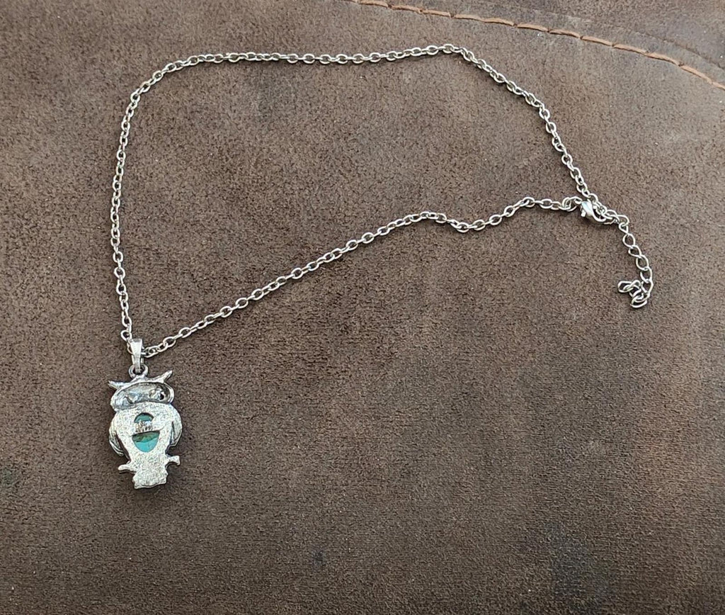 Silver-tone owl pendant necklace shown at an angle with turquoise stone center