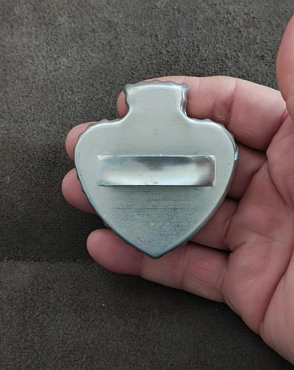 Silver spade-shaped cookie cutter held in hand, back view with wide handle
