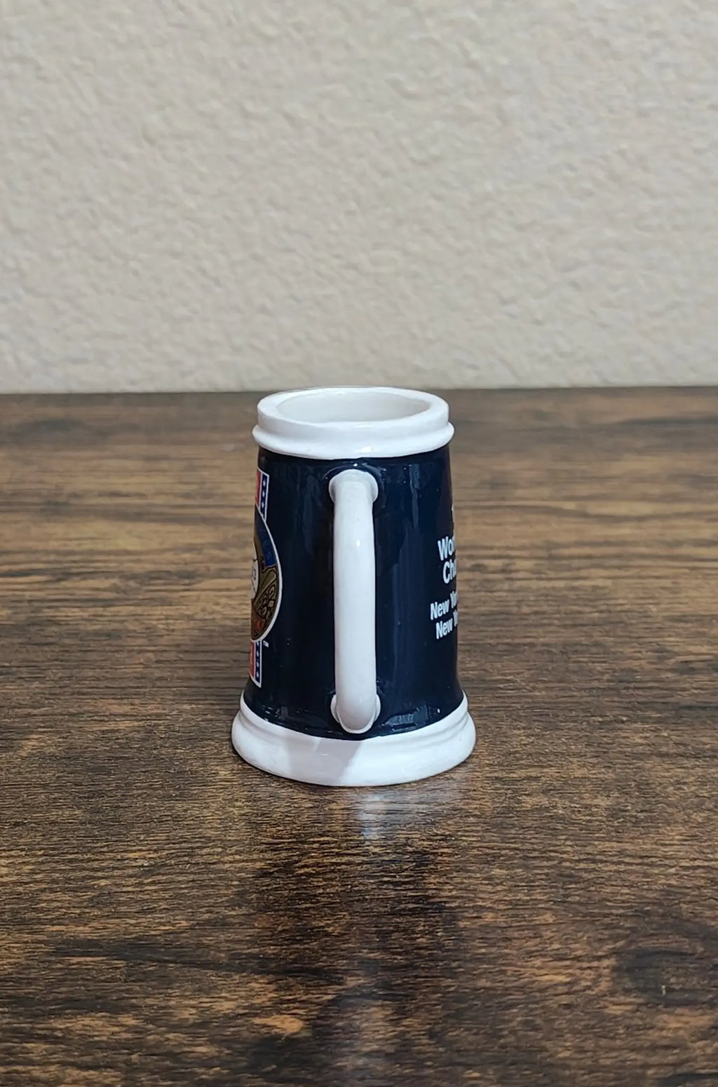 Dark blue mini mug side view with vertical handle and partial printed text.