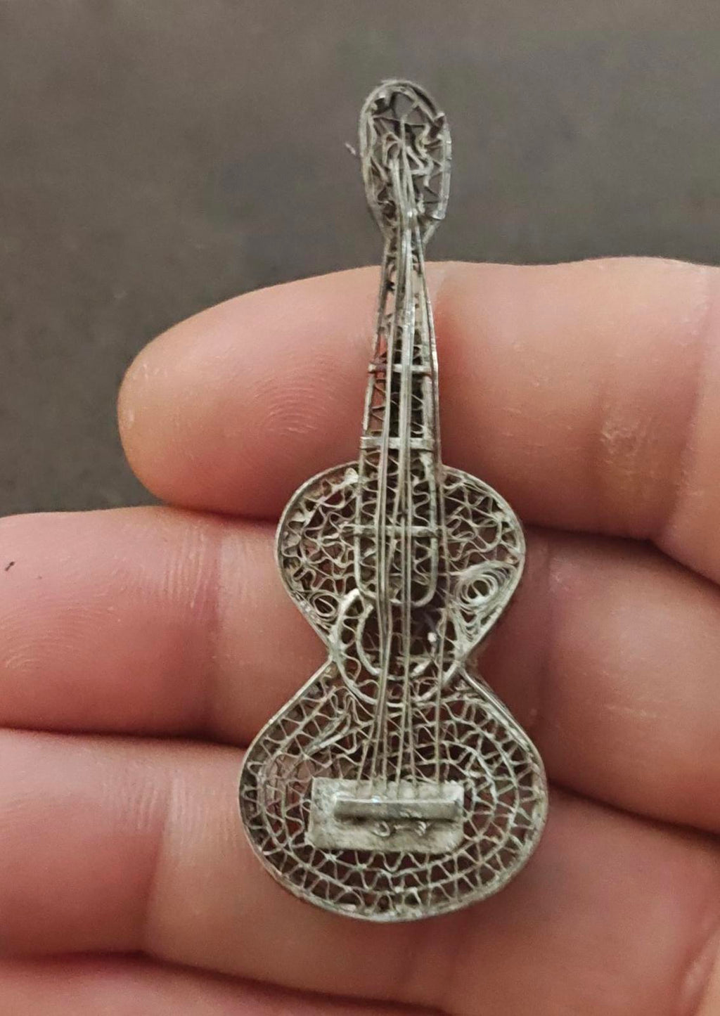 Sterling silver filigree guitar brooch pendant close-up on textured wirework