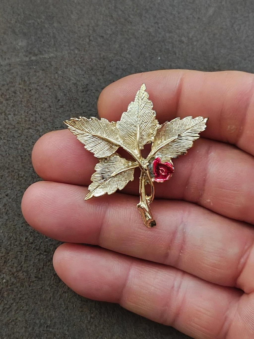 Gold-tone leaf cross pin brooch with red rose and Mary medallion on hand
