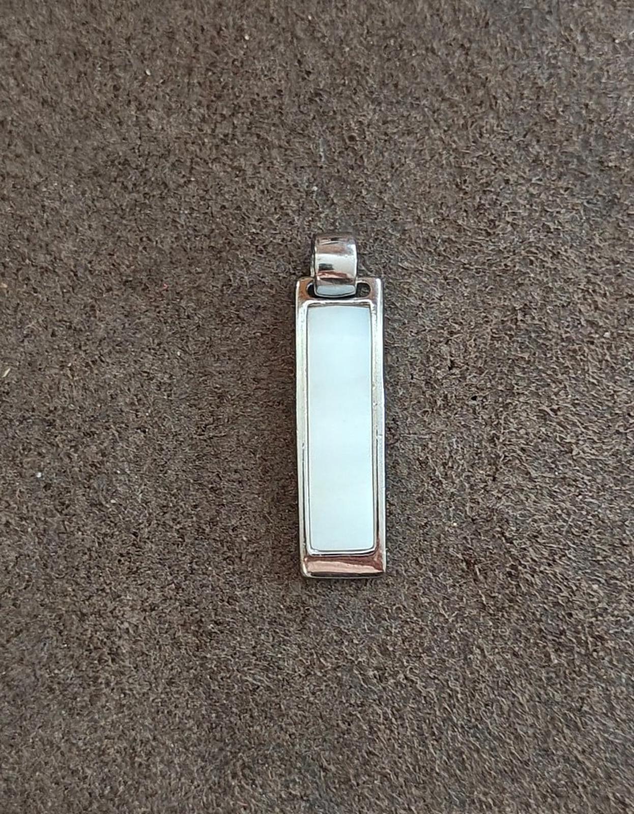 Silver-tone rectangular slide pendant with light inset window; bail attachment at top.