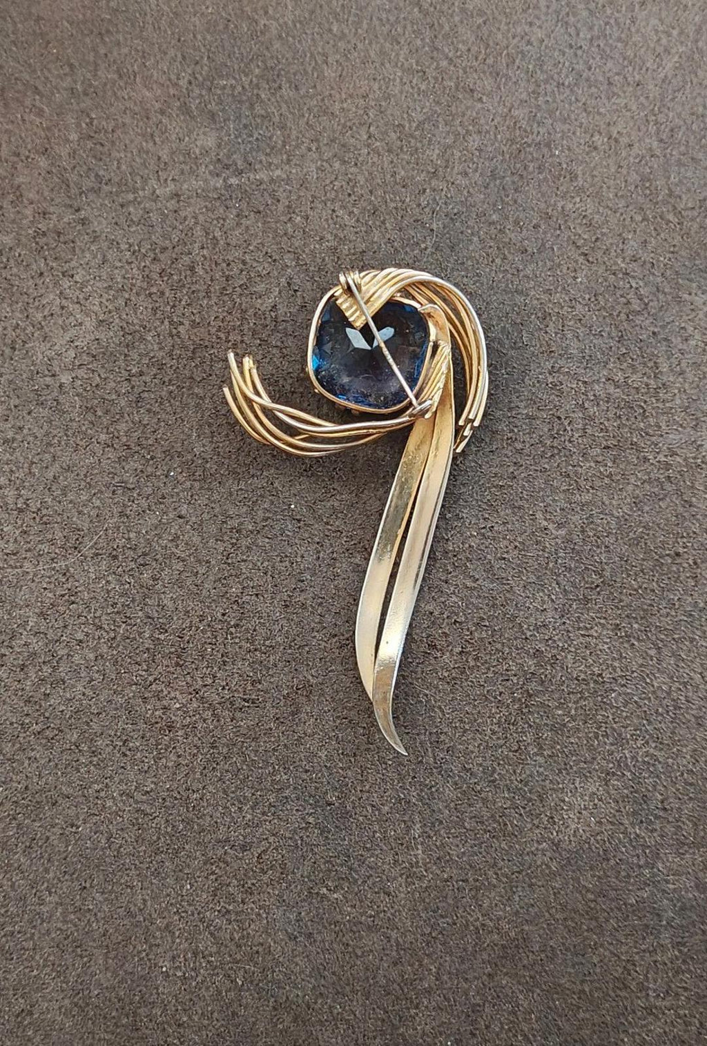 Gold-tone abstract brooch pin with blue gemstone and long curved center bar