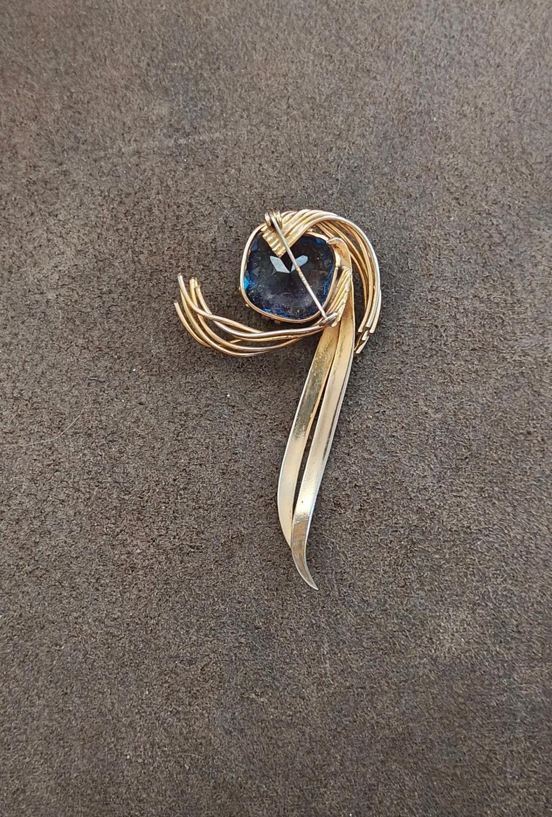 Gold-tone abstract brooch pin with blue gemstone and long curved center bar
