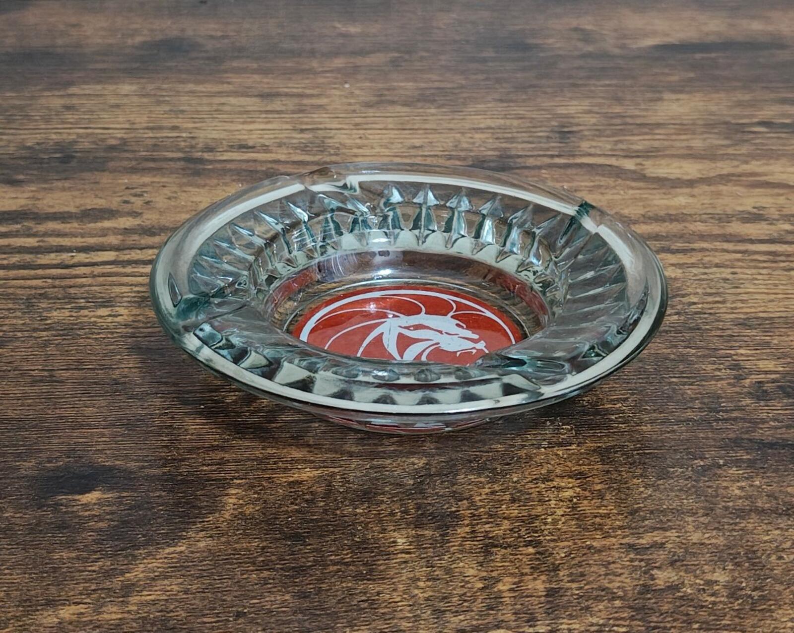 Clear glass ashtray, top angle showing red logo under faceted rim