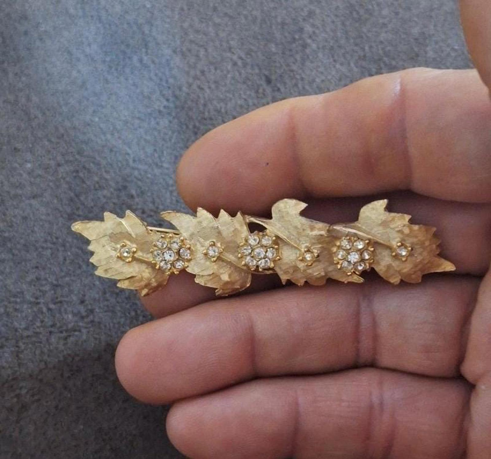 Gold tone leaf and flower rhinestone brooch pin with small round crystal accents