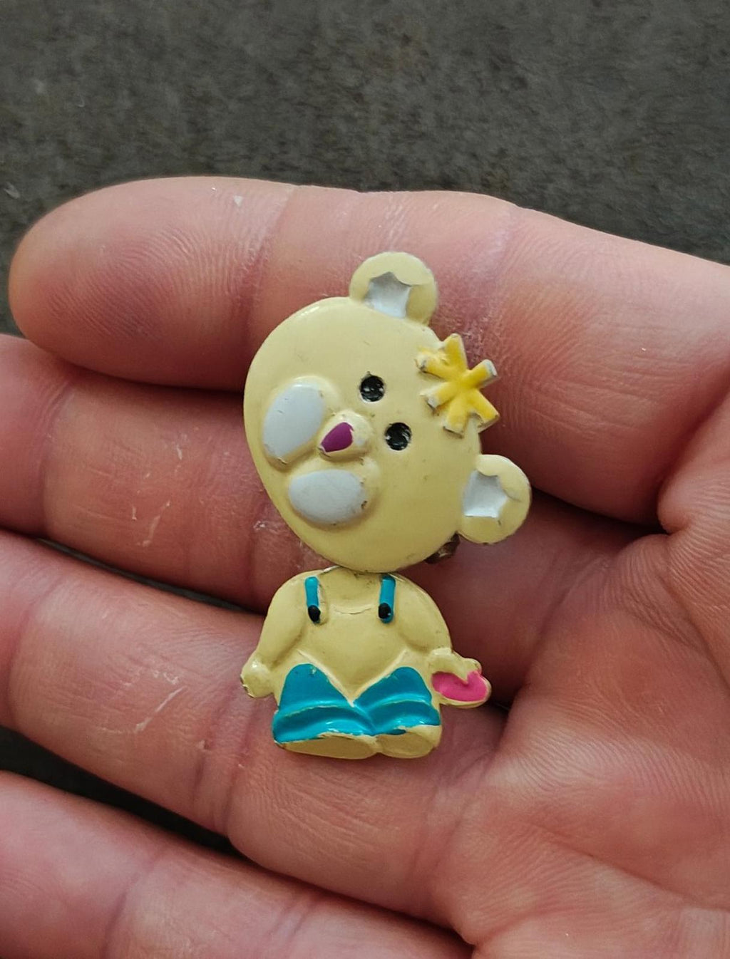Yellow enamel teddy bear brooch side view with star hair, teal dress, and pink bow
