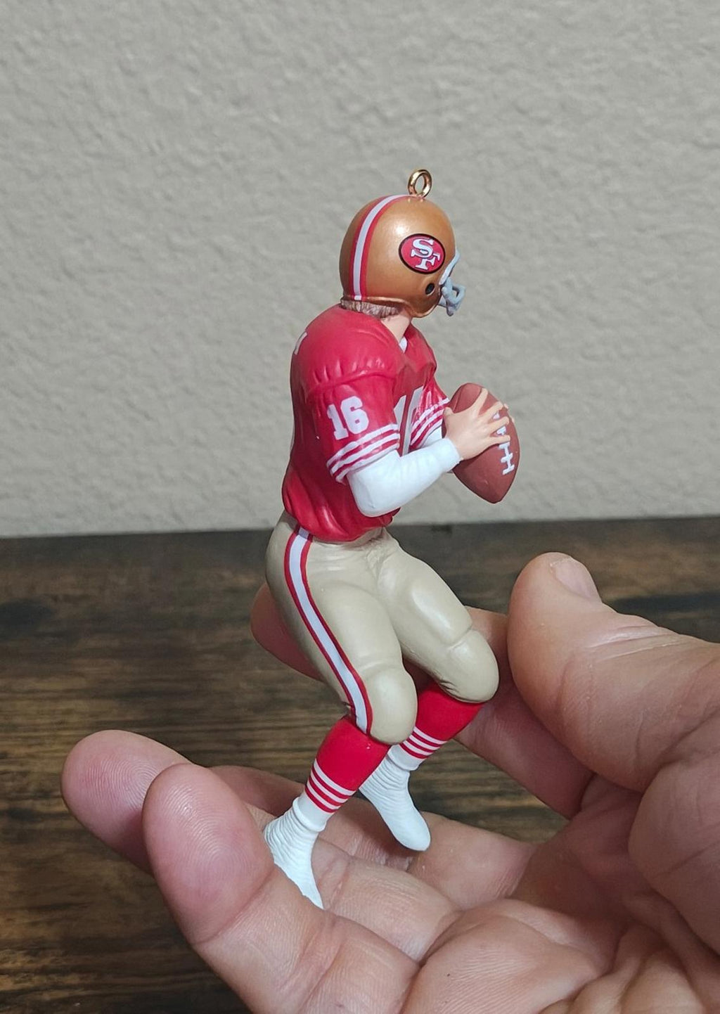 Side view red football player ornament with jersey 16, standing with arms crossed