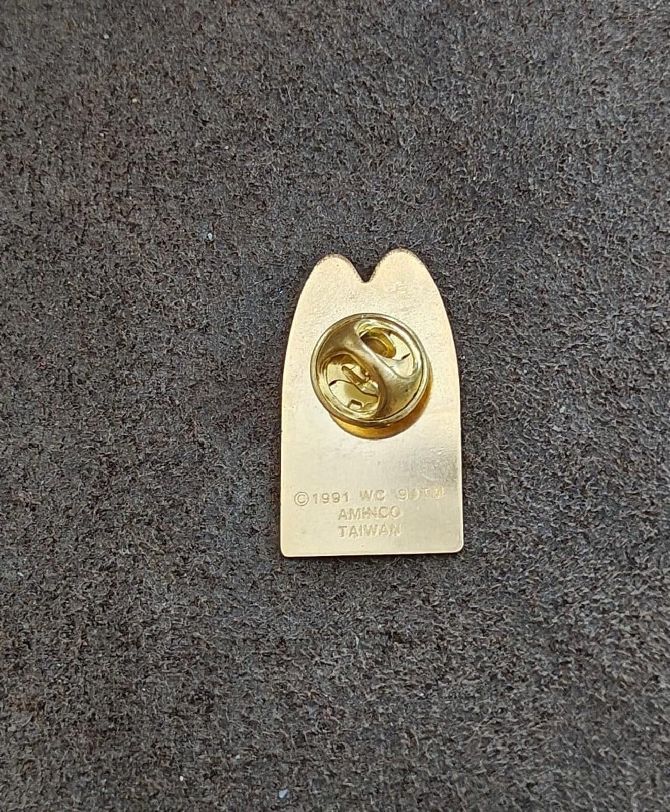 Gold-tone pin back with round safety clasp and stamped markings