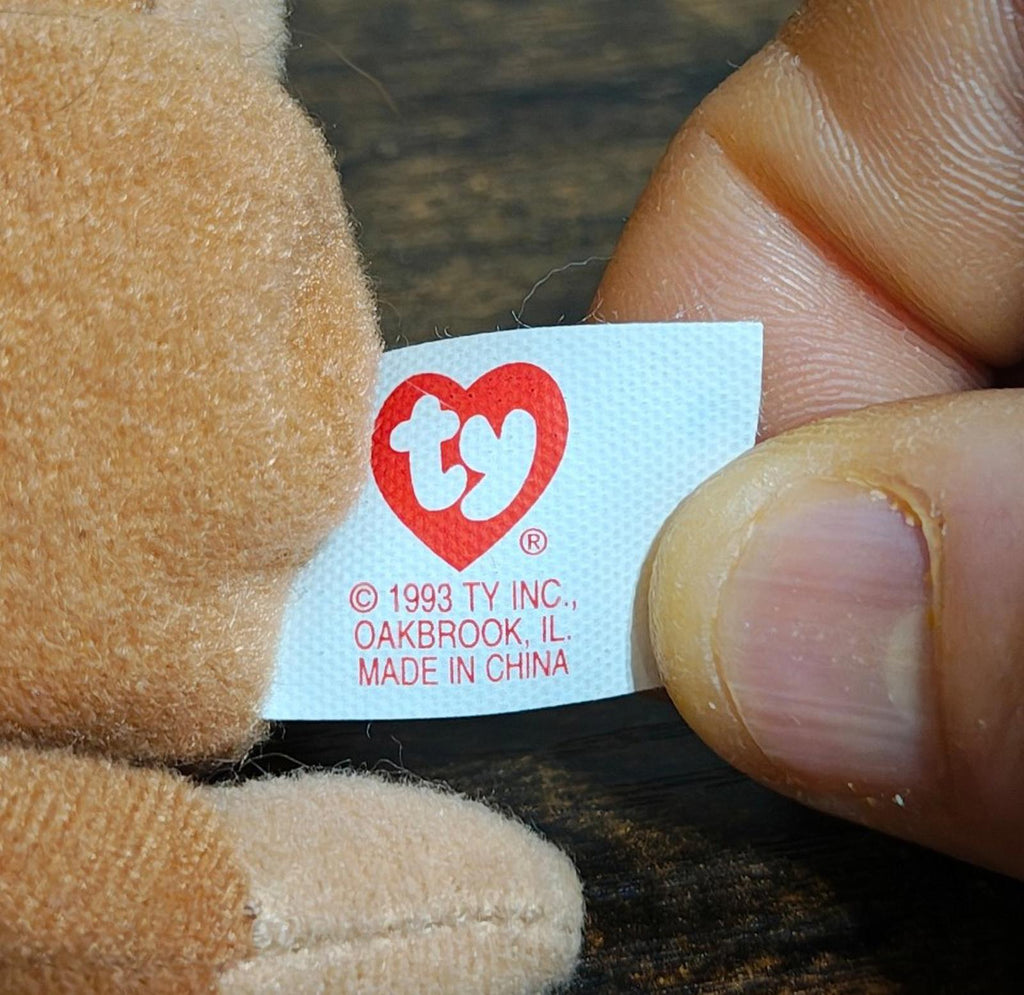 Close-up of Ty heart tag on brown plush monkey, near the brand text