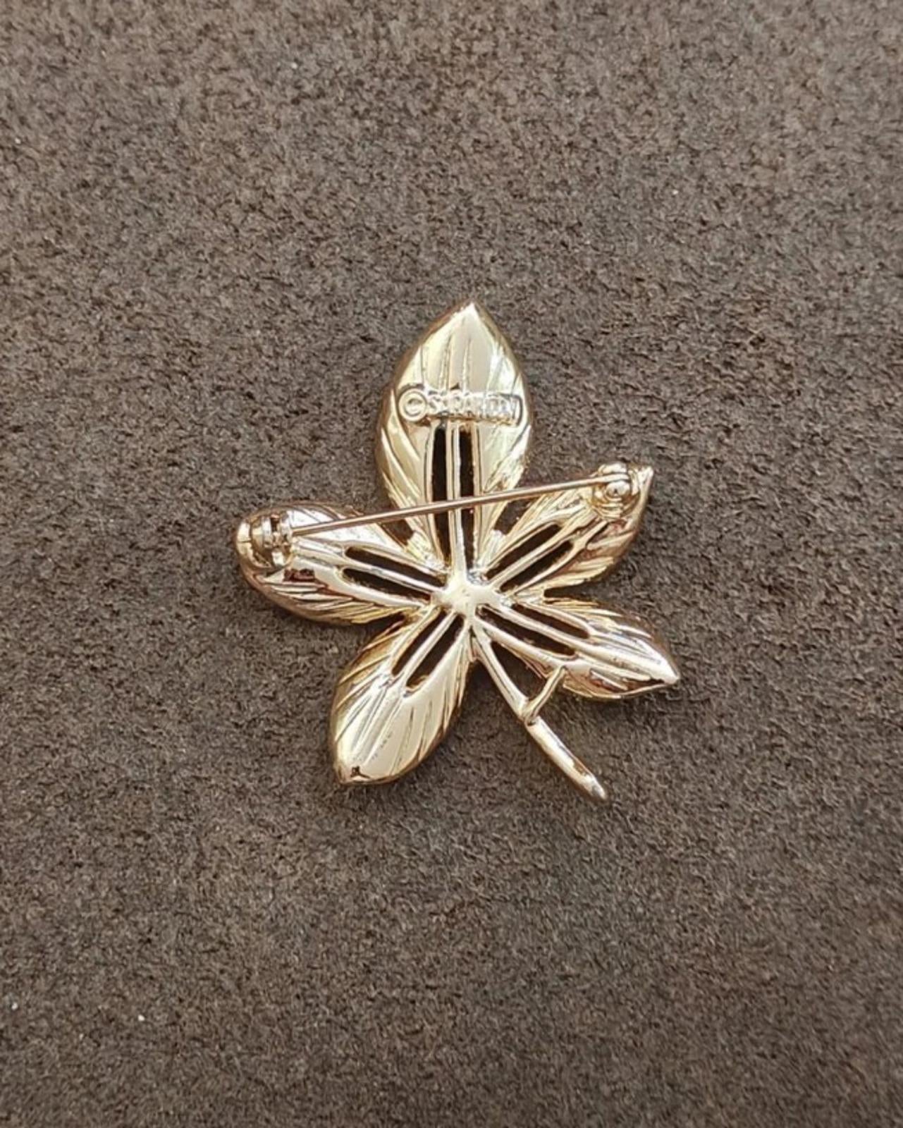 Gold-tone leaf flower brooch with raised ridges and small hinge-like bar accents