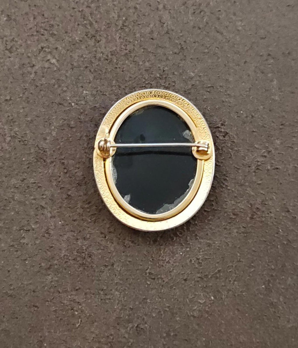 Gold-tone brooch back with oval frame and pin clasp, black center panel