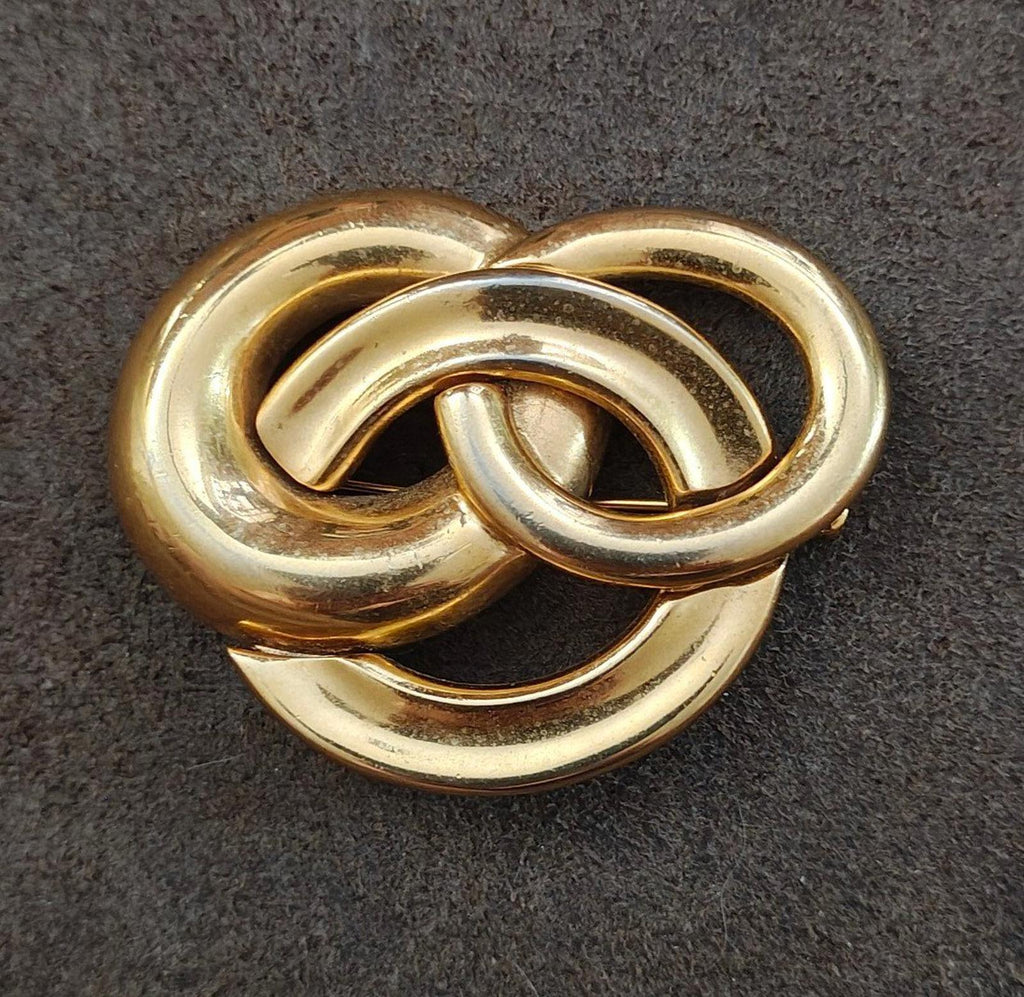 Gold-tone heart-like pin brooch with three intertwined circles, close-up