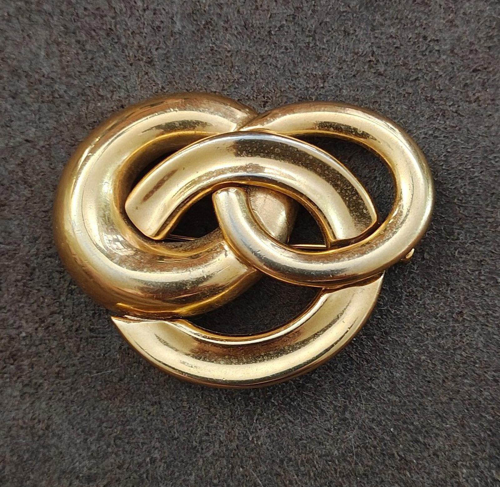 Gold-tone heart-like pin brooch with three intertwined circles, close-up