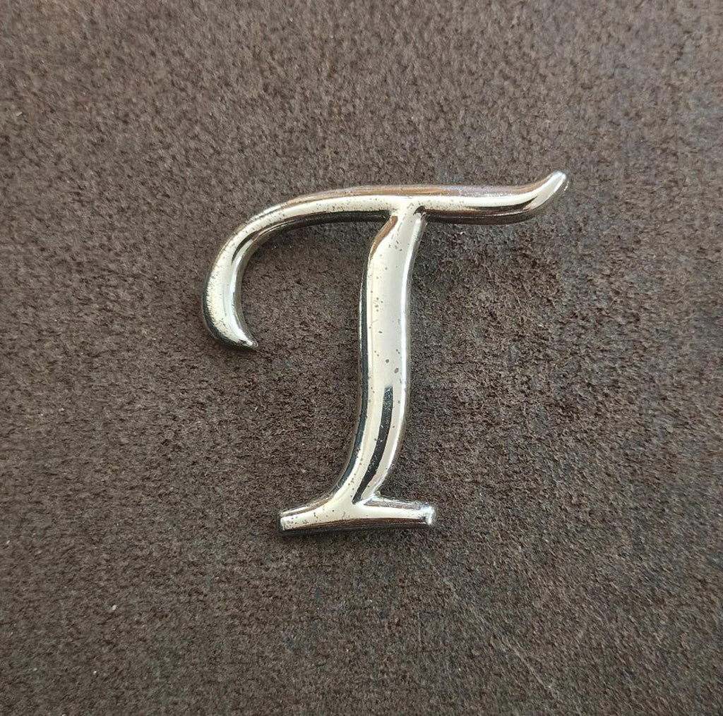 Silver-tone monogram letter T pin/brooch, centered view showing smooth finish.
