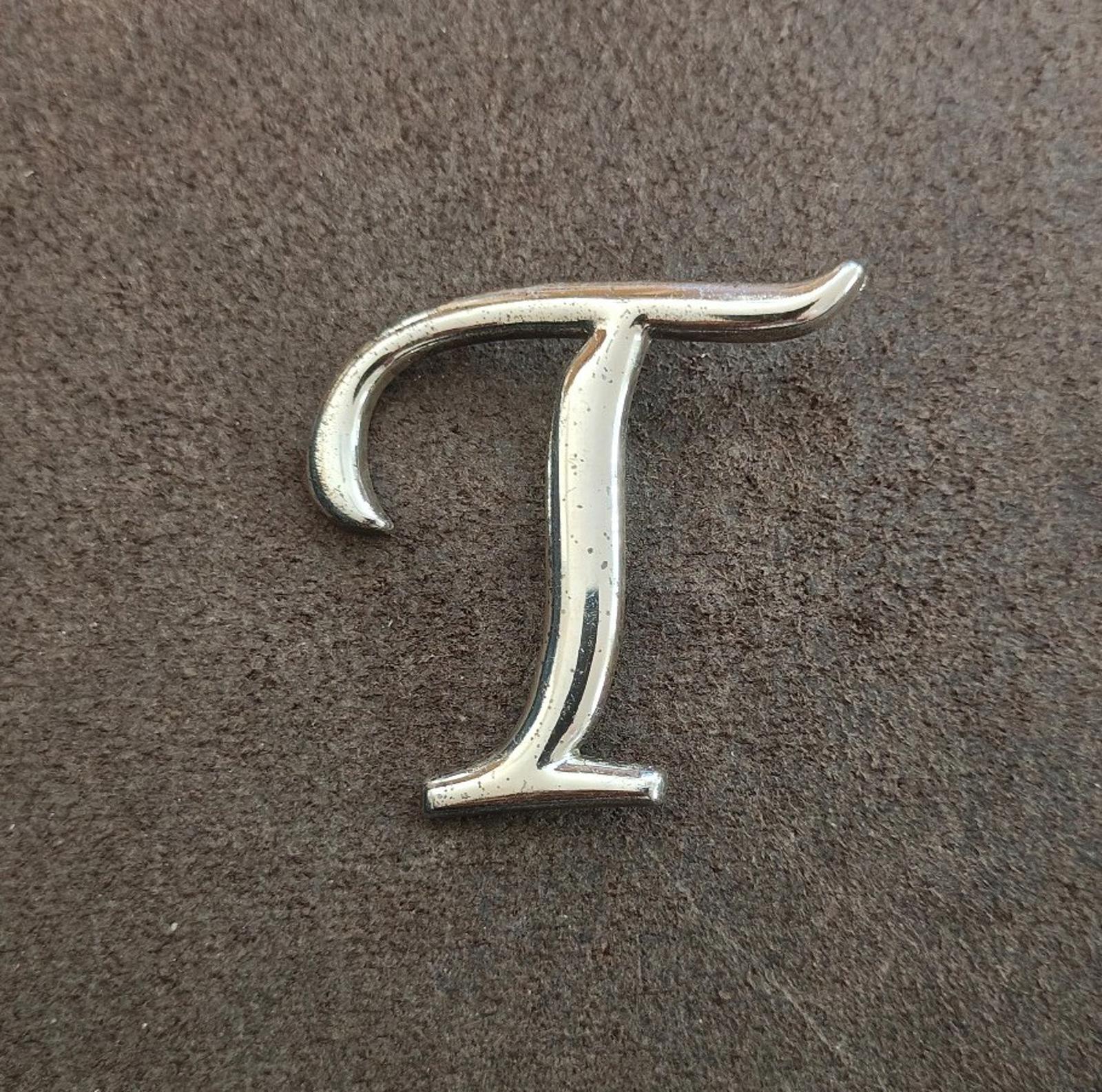 Silver-tone monogram letter T pin/brooch, centered view showing smooth finish.