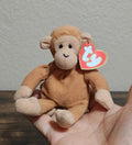 Brown Ty Beanie Babies plush monkey with heart tag, sitting in open hands