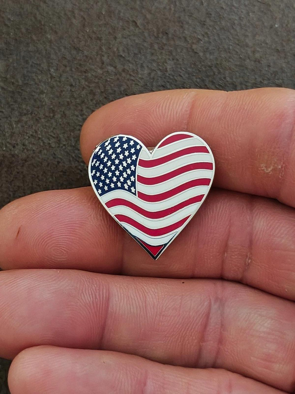 Heart-shaped enamel flag pin with blue stars and red/white wavy stripes, silver edging