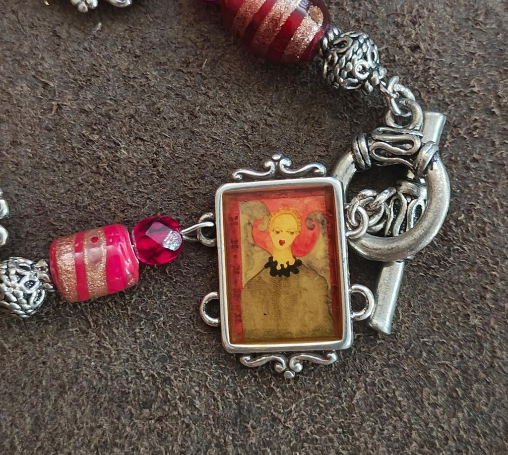 Silver letter charm and angel portrait frame on bracelet with red striped beads and blue accents