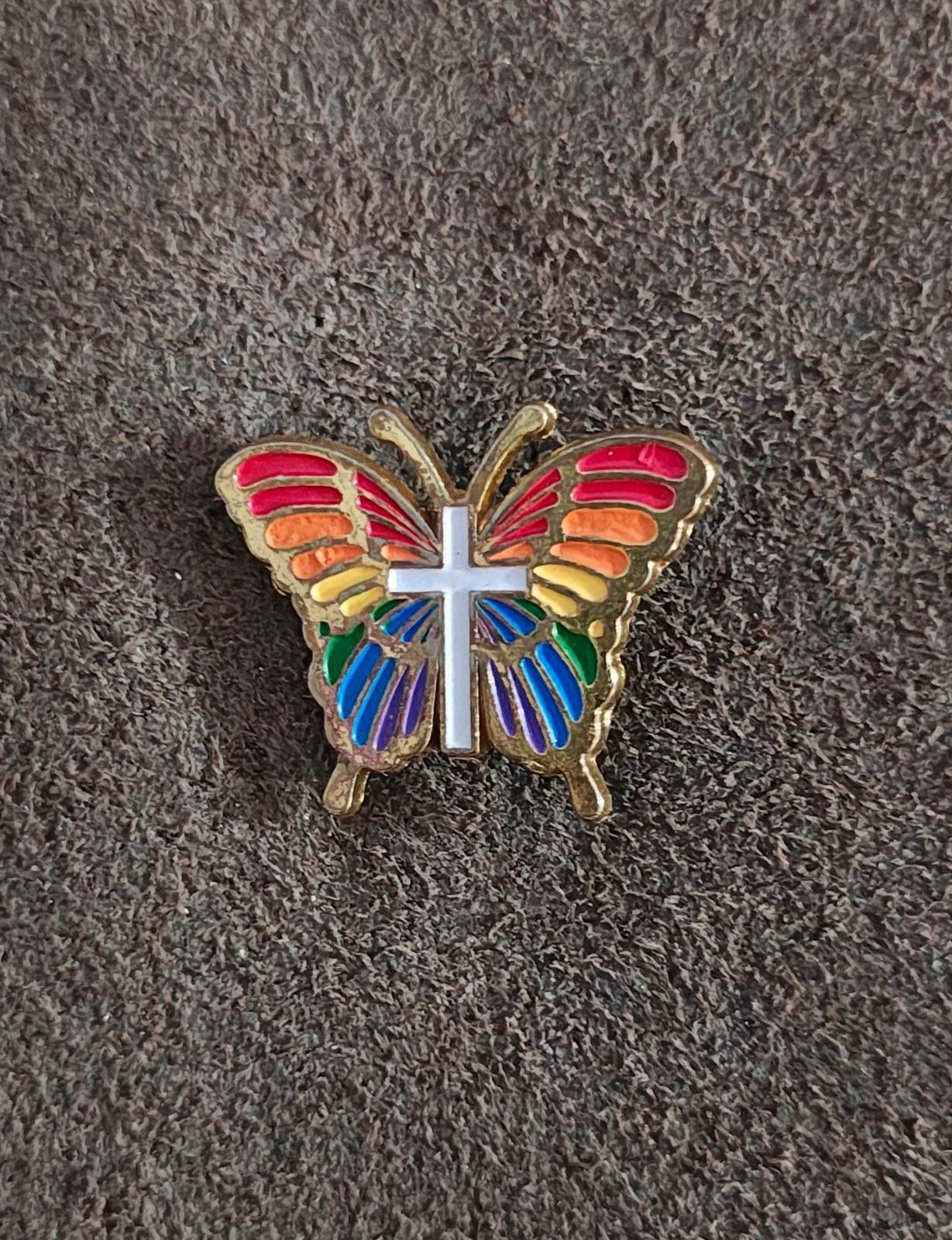 Rainbow butterfly enamel pin with gold-tone edges and white cross