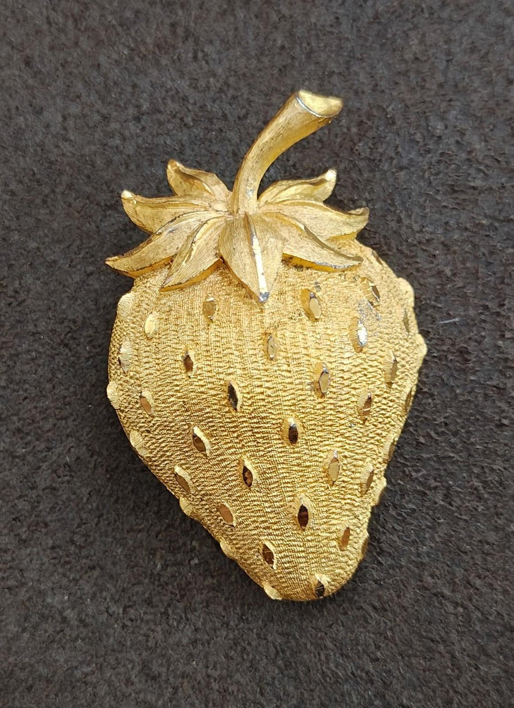 Gold tone strawberry brooch pin with stem, raised leaves, and dotted seed detailing.