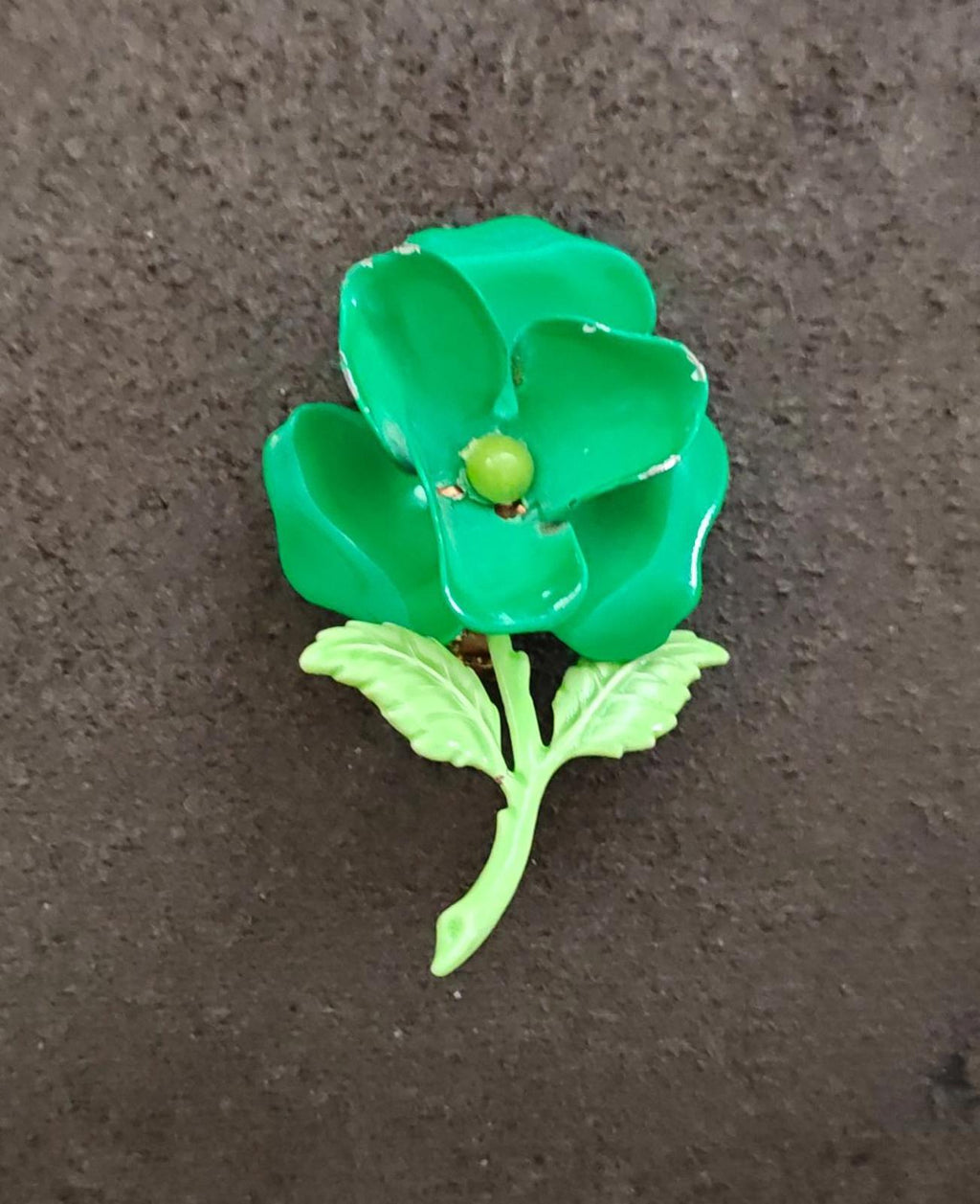 Green enamel flower brooch with gold center and light green leaf accents.