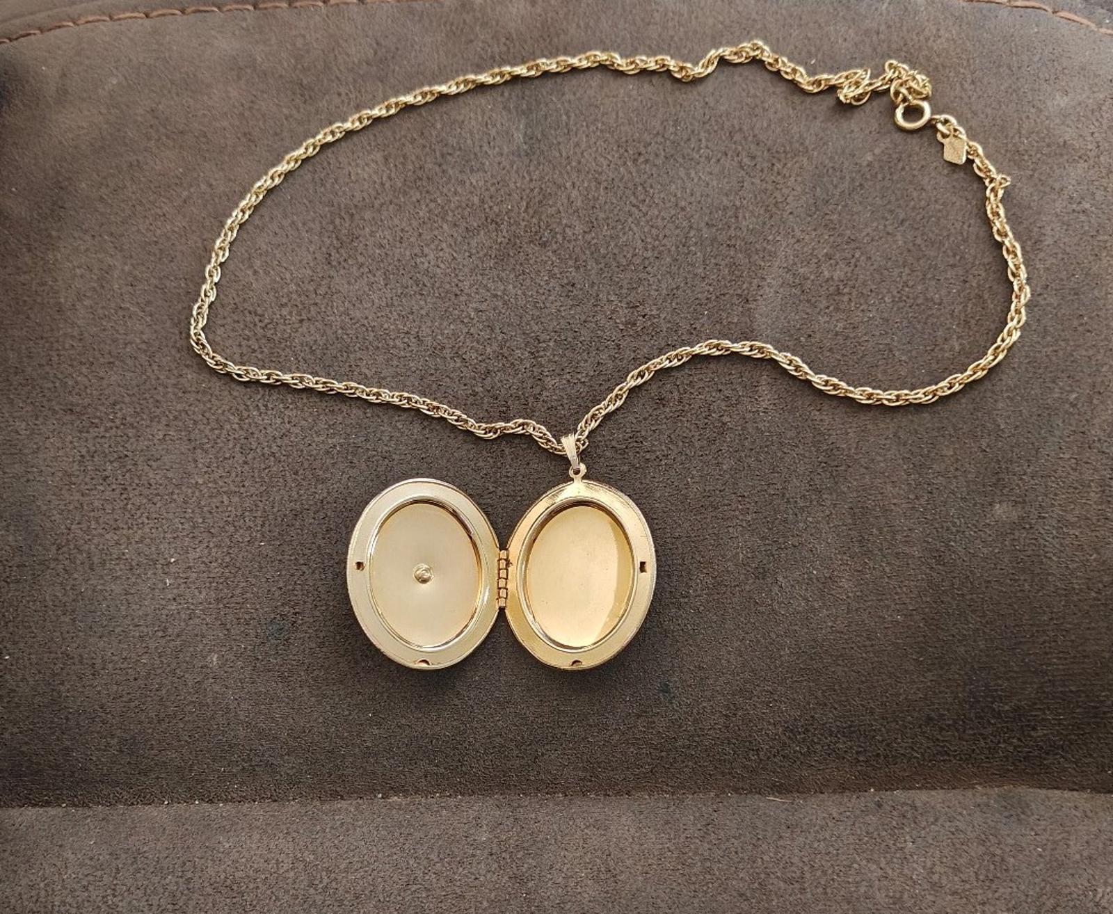 Gold-tone locket necklace with chain, open oval pendant showing two cream interiors