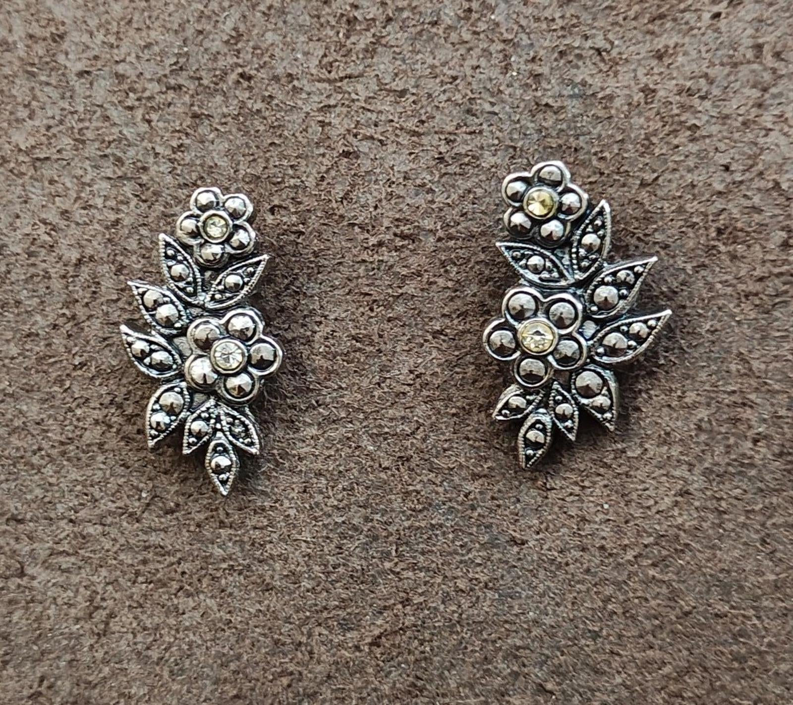 Silver tone floral leaf stud earrings featuring clustered round rhinestones