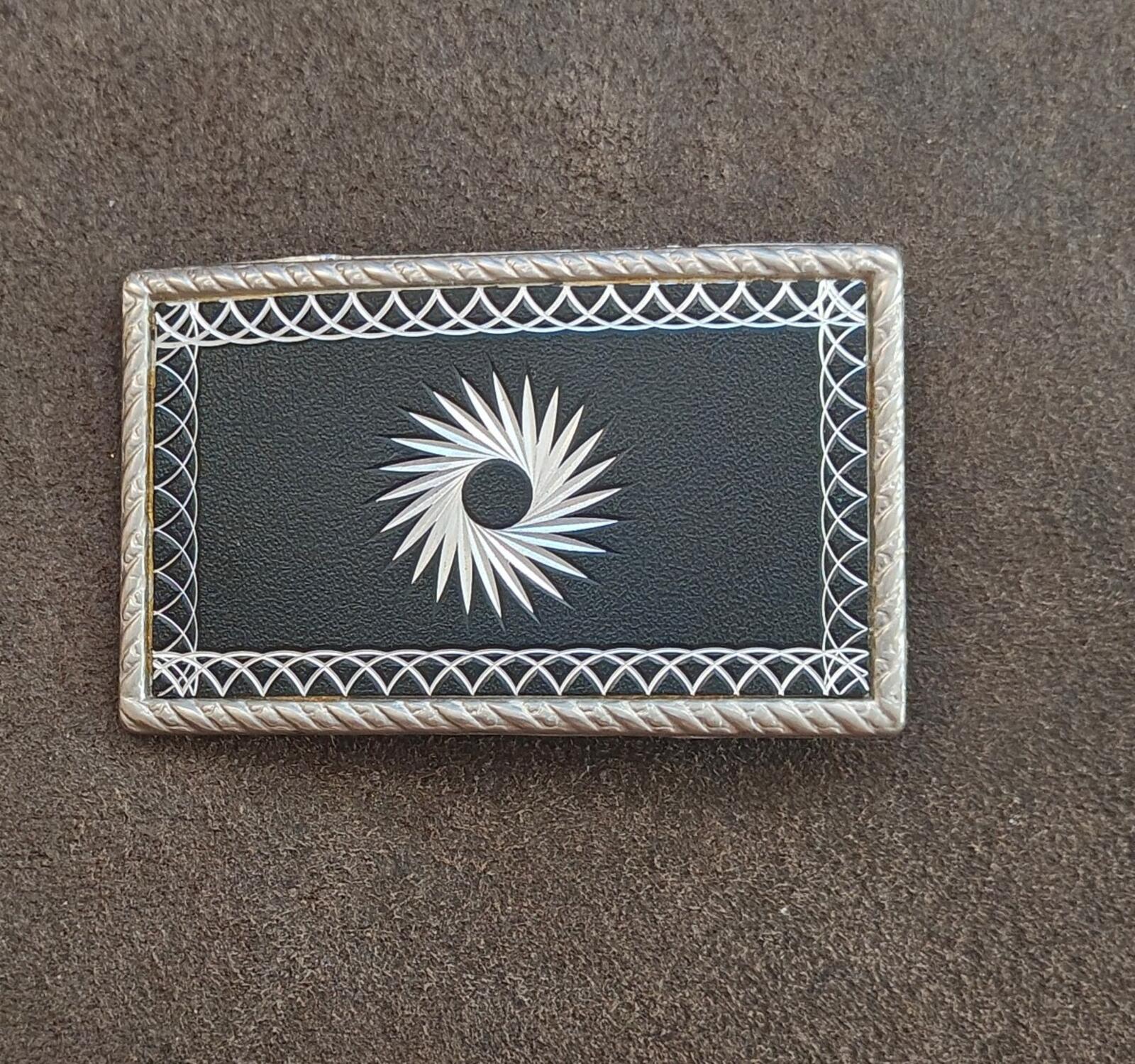 Western belt buckle front view: silver starburst motif on black background