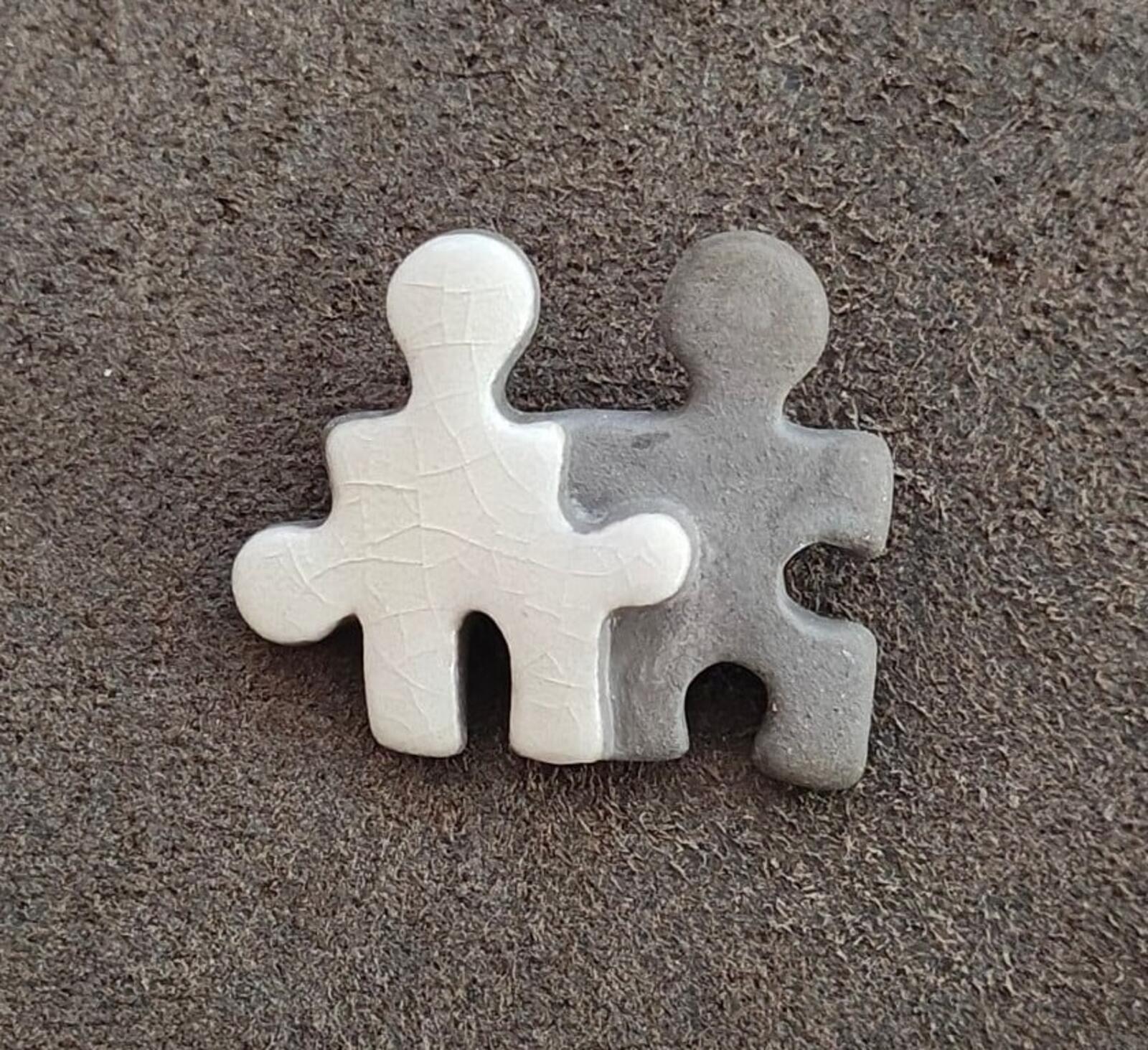 Two joined puzzle buddy figures brooch in white and gray, flat ceramic texture