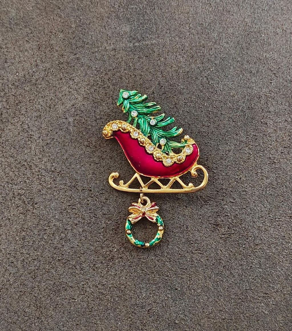 Gold and enamel Christmas sleigh pin with green tree topper and hanging wreath ornament.