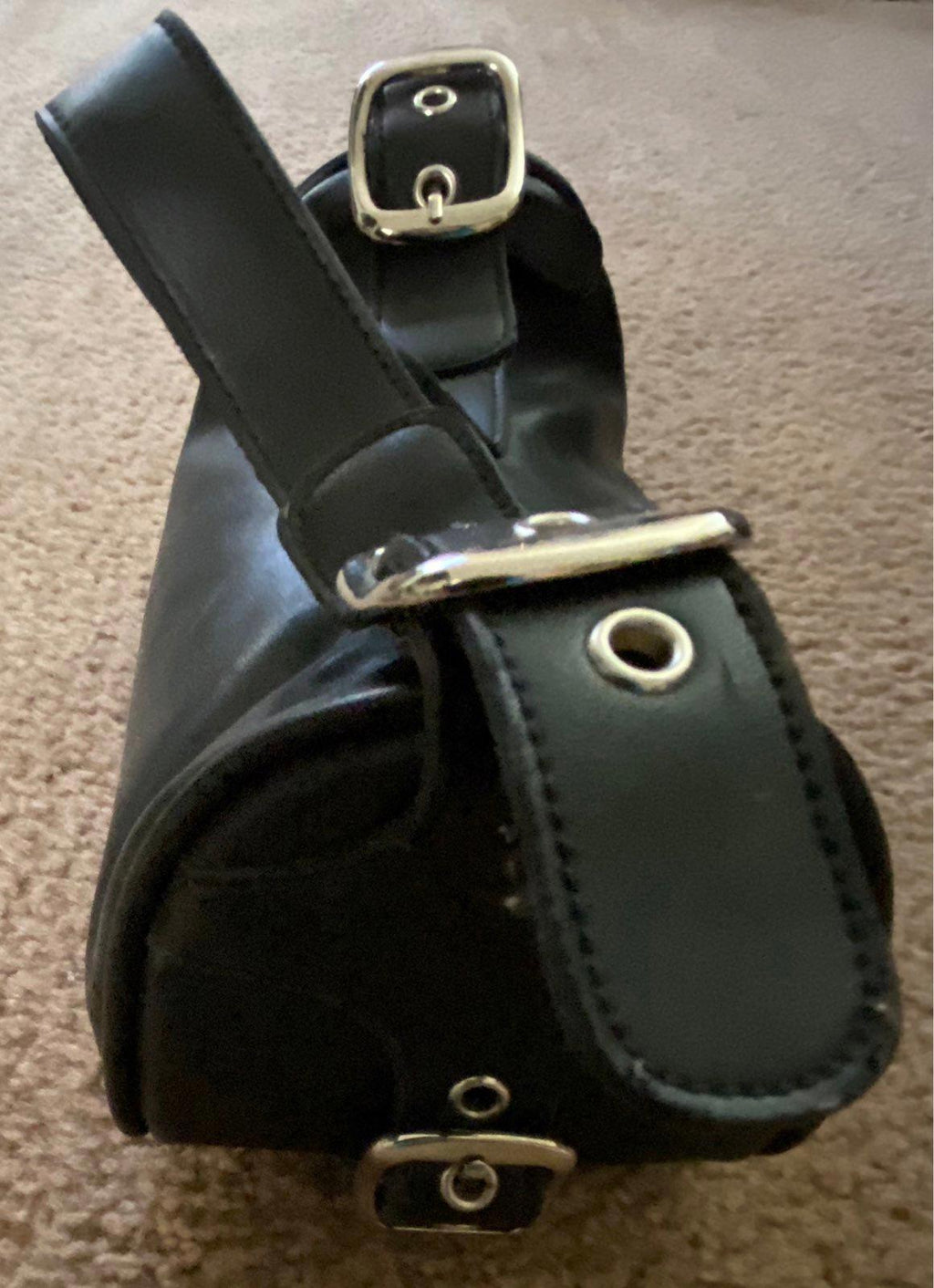 Black leather purse with double strap buckles and metal rings at base