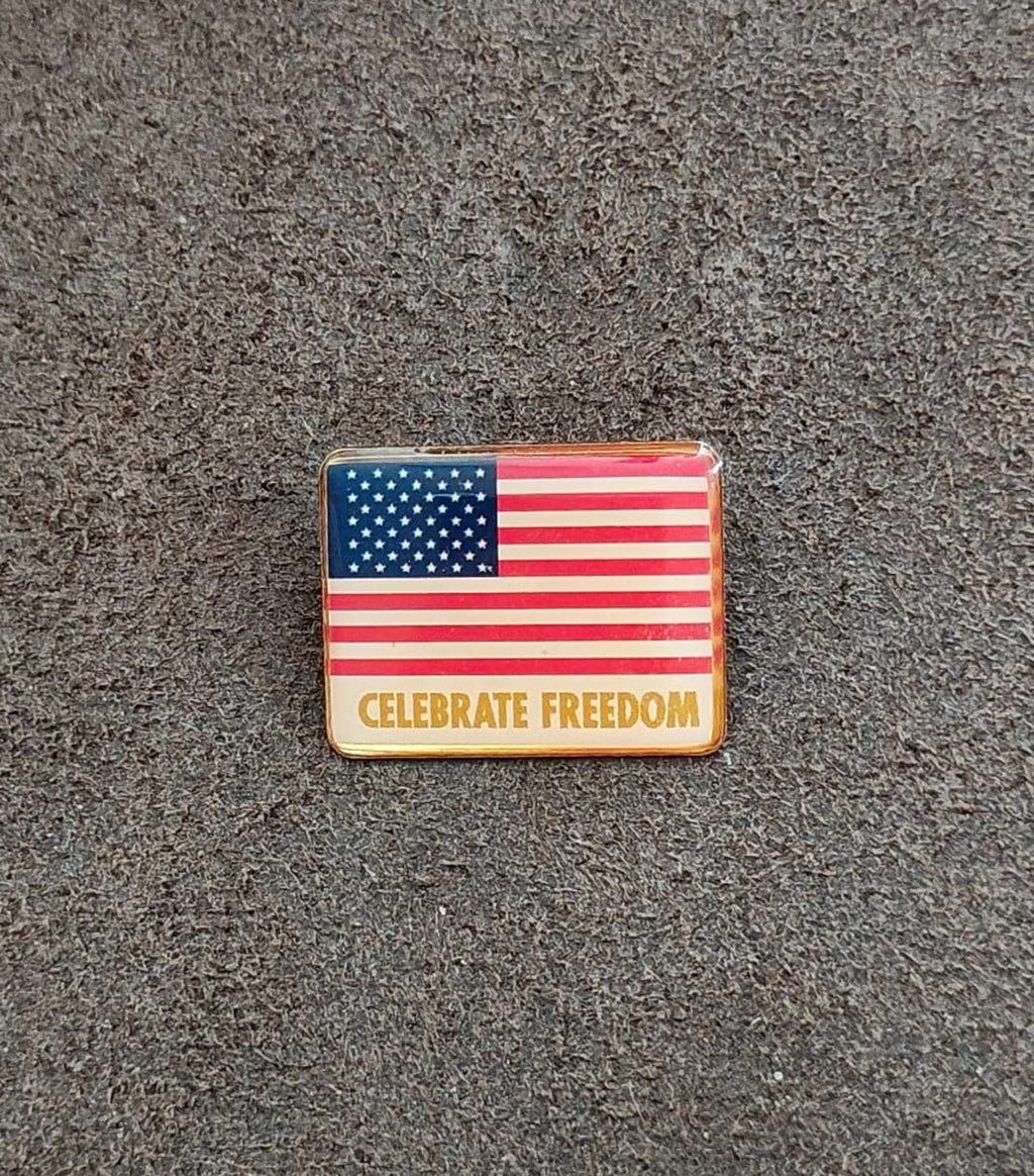 Rectangular gold-tone flag pin reading “CELEBRATE FREEDOM” on the front