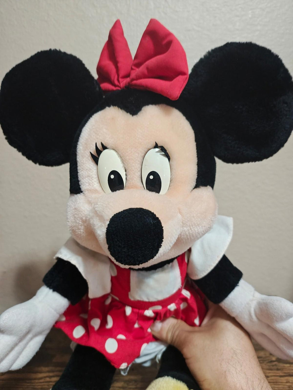 Minnie Mouse plush face with red bow and polka-dot dress, white collar and gloves