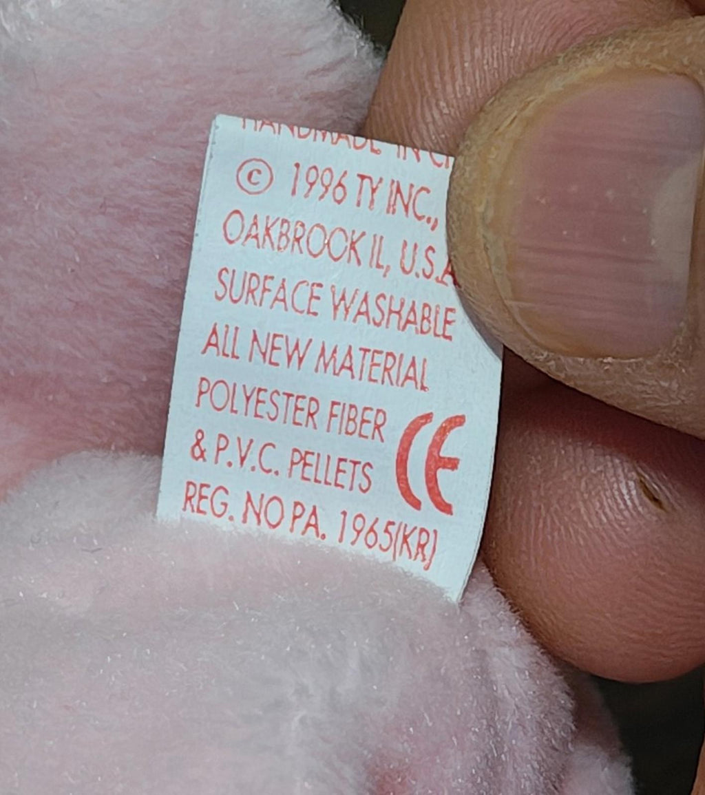 White fabric label with care and material info on pink plush bunny