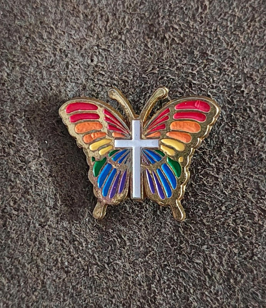 Rainbow butterfly enamel pin with white cross, multicolor wings, gold-tone border