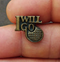 Gold tone lapel pin with "I WILL GO" text and globe-style emblem, front close-up